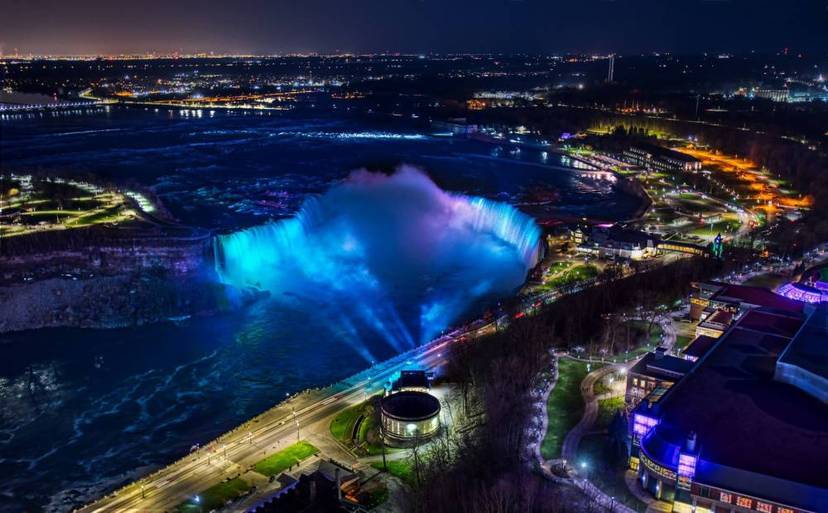 Aerial night view of Niagara Falls illuminated with the Illumination Tower in the foreground.