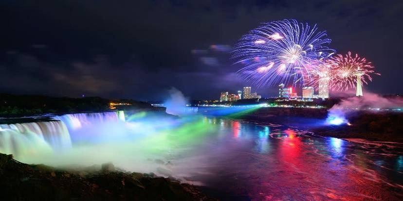 Fireworks over illuminated Niagara Falls at night.