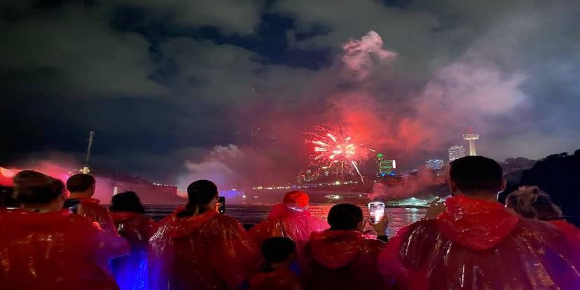 Visitors on a Niagara Falls boat cruise with fireworks overhead.