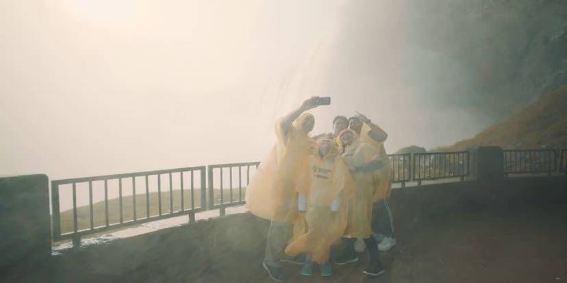 Visitors in yellow ponchos taking selfie at Journey Behind the Falls