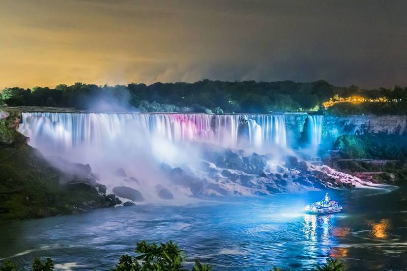Niagara City Cruises boat with illuminated Niagara Falls at night.