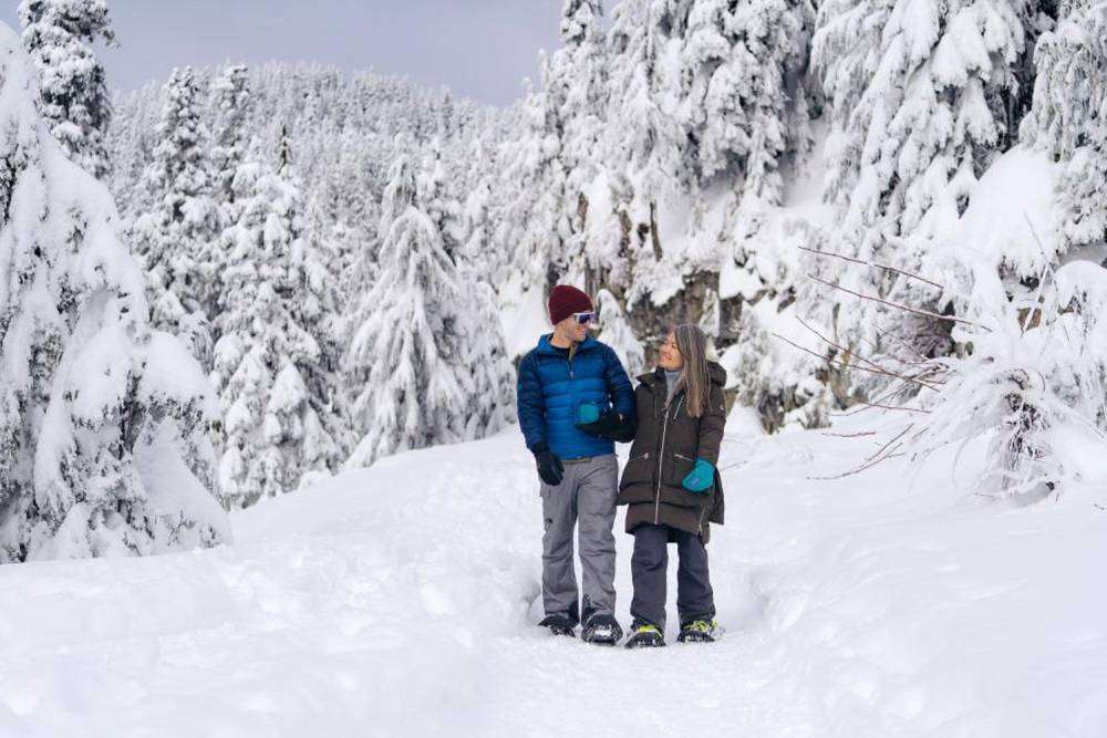 A couple is snow shoeing on Grouse Mountain